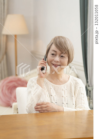家の電話で楽しくおしゃべりするシニア女性 家の電話で楽しくおしゃべりするシニア女性 132011058