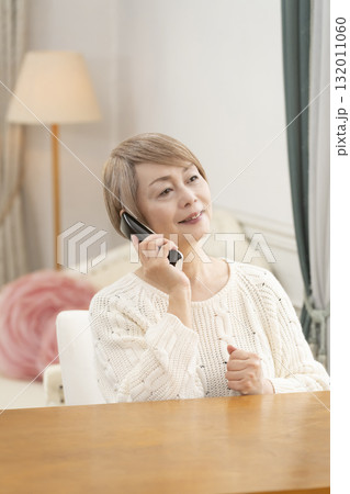 家の電話で楽しくおしゃべりするシニア女性 家の電話で楽しくおしゃべりするシニア女性 132011060