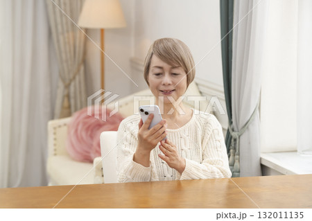 スマートホンで楽しくおしゃべりしたり検索したりするシニア女性 スマートホンで楽しくおしゃべりしたり検索したりするシニア女性 132011135