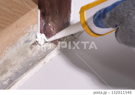 Handyman use acrylic sealant on hole of base door frame for protect underground insects pass through. Handyman use acrylic sealant on hole of base door frame for protect underground insects pass through. 132011348