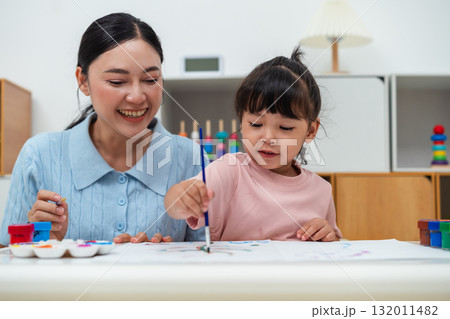 happy mother and toddler girl painting watercolor in paper at home happy mother and toddler girl painting watercolor in paper at home 132011482