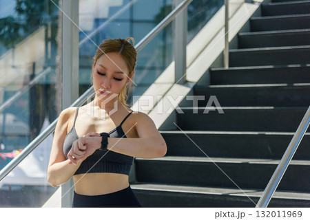 Stretch muscles, woman prepares for sport workout outdoor, fit person reviews exercise progress on smartwatch, essential stretch for active people. 132011969