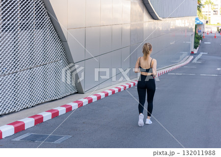 Stretch for flexibility, fit woman sport exercise workout outdoor, walking modern city street, healthy lifestyle promoting body movement, ideal way to stretch and stay active. 132011988