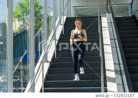 Fit woman performing sport exercise, workout outdoor, descending stairs, healthy living, achieving strong fit physique, exhibiting stretch, inspiring active people. 132012107