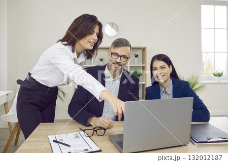 woman employee showing something to her colleagues on the monitor screen on workplace in office. 132012187