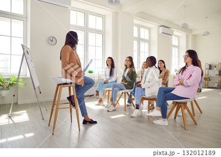 Young woman coach gives presentation for diverse women at professional business training meeting 132012189