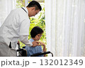 Caring doctor comforting an elderly female patient in a wheelchair at home or clinic. Concept of healthcare, compassion, medical support, and trust between doctor and patient in professional 132012349