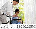 Doctor gently comforting an elderly female patient in a wheelchair near bright window at clinic or home. Concept of healthcare, compassion, recovery, and emotional support between doctor and patient 132012350