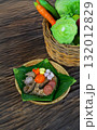 Thai Traditional "Khao Hor Bai Bua" (Lotus Leaf Wrapped Rice): Savory steamed rice mixed with meat, mushrooms, and spices on an old wooden table with vegetable basket 132012829