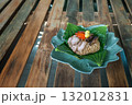 Steamed sticky rice wrapped in lotus leaf, filled with minced pork, ginkgo, Chinese sausage, and salted egg yolk on an antique wooden table 132012831