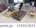 A classic vintage camera, leather journals, premium cigars in a wooden box, and a bottle of amber liquor on a modern table, suggesting luxury, travel, and refined leisure. 132012833
