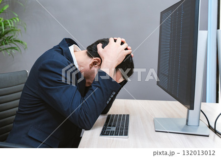 Young Businessman or Programmer looking worried and stressed over working on a computer code at office. Young Businessman or Programmer looking worried and stressed over working on a computer code at office. 132013012