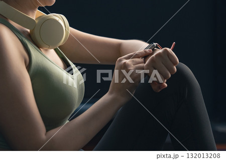 Young Asian woman in sportswear checking her workout results on a smart watch while resting at the gym. 132013208