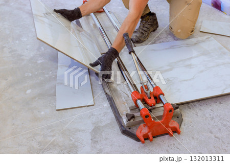 Contractor is carefully cutting tiles on floor for home renovation progress. Contractor is carefully cutting tiles on floor for home renovation progress. 132013311