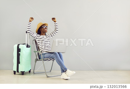 African American woman with suitcase and laptop gets happy when she books cheap holiday tickets African American woman with suitcase and laptop gets happy when she books cheap holiday tickets 132013566