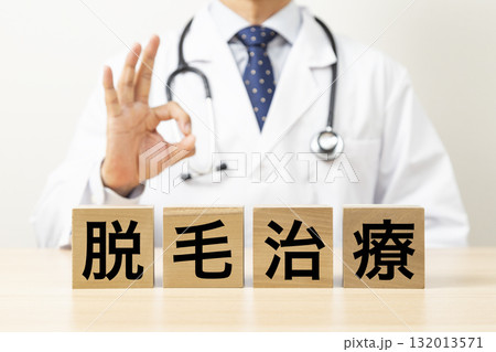 「脱毛治療」と書かれたブロックとOKサインをする医師 132013571