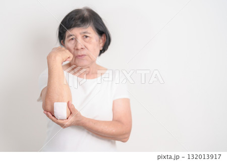 Elderly Woman having elbow ache with Medicated pain relief patch plaster for concepts of Tennis Elbow, muscle pain and Sprain, lateral epicondylitis, Bursitis, injury, Senior Health care and medical 132013917