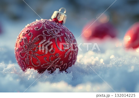Red Christmas ornament with intricate design resting on fresh snow in a winter wonderland scene Red Christmas ornament with intricate design resting on fresh snow in a winter wonderland scene 132014225