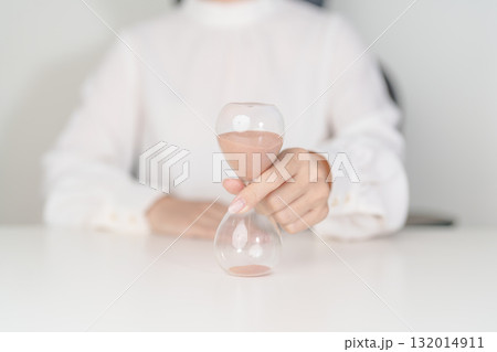 Woman with Hourglass on table office, Sand flowing through the bulb of Sandglass measuring the passing time. countdown, deadline, Life time and Retirement concept 132014911
