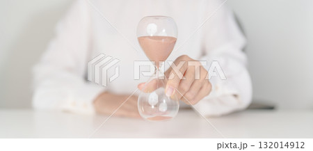 Woman with Hourglass on table office, Sand flowing through the bulb of Sandglass measuring the passing time. countdown, deadline, Life time and Retirement concept 132014912
