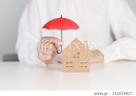 Woman hand holding red Umbrella cover wooden Home model. real estate, insurance and property concepts 132014927