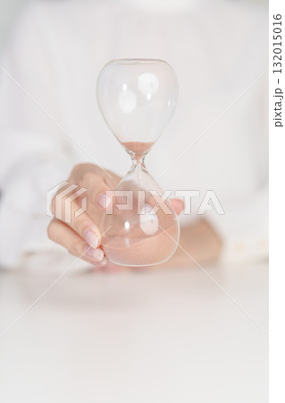 Woman with Hourglass on table office, Sand flowing through the bulb of Sandglass measuring the passing time. countdown, deadline, Life time and Retirement concept 132015016