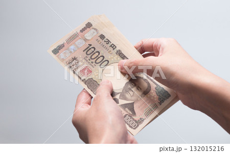 手に持った現金10万円を手渡す・受け取る写真 (新紙幣・一万円札・渋沢栄一・白バック) 132015216