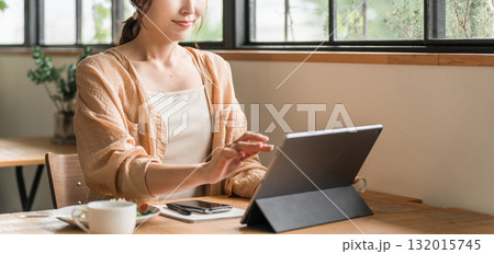 カフェでコーヒーを飲みながらテレワークをする女性 132015745