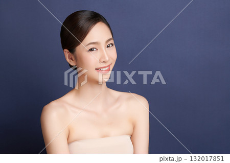 A beautiful young Asian woman with clean, fresh skin against a blue background. Skincare, facial treatment, cosmetology, beauty, and spa. An elegant portrait of an Asian woman. A beautiful young Asian woman with clean, fresh skin against a blue background. Skincare, facial treatment, cosmetology, beauty, and spa. An elegant portrait of an Asian woman. 132017851