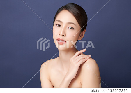 A beautiful young Asian woman with clean, fresh skin against a blue background. Skincare, facial treatment, cosmetology, beauty, and spa. An elegant portrait of an Asian woman. A beautiful young Asian woman with clean, fresh skin against a blue background. Skincare, facial treatment, cosmetology, beauty, and spa. An elegant portrait of an Asian woman. 132017852
