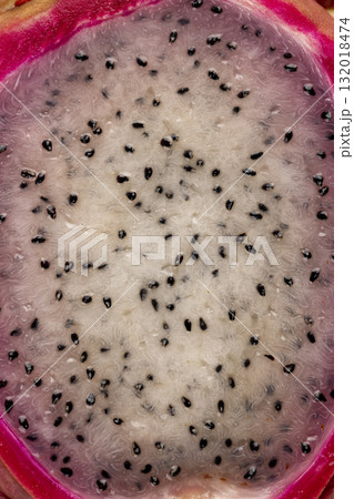 red pitaya cut in half with lots of small black seeds and white soft sweet flesh inside, sweet ripe dragon fruit with black small seeds and light flesh cut in half 132018474
