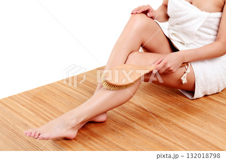 Woman is massaging skin on her legs with big brush, isolated on white background Woman is massaging skin on her legs with big brush, isolated on white background 132018798