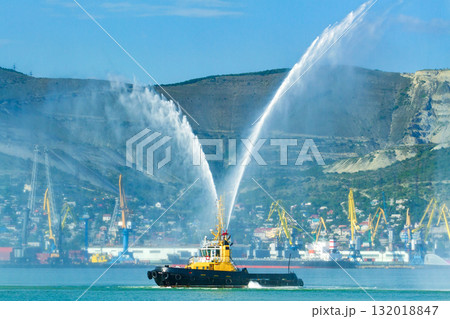 Floating tug boat is spraying jets of water, demonstrating firefighting water cannons Floating tug boat is spraying jets of water, demonstrating firefighting water cannons 132018847
