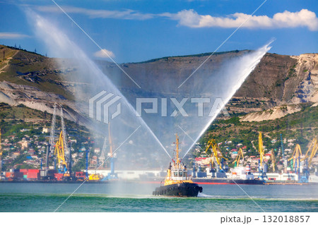 Floating tug boat is spraying jets of water, demonstrating firefighting water cannons Floating tug boat is spraying jets of water, demonstrating firefighting water cannons 132018857