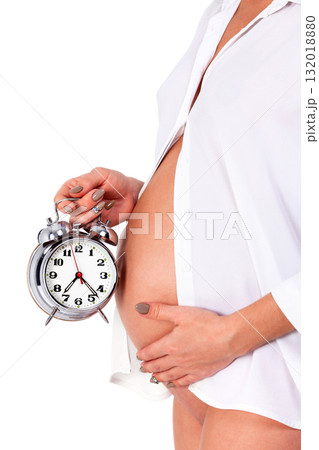 Closeup shot of pregnant woman who holds an alarm clock. Isolated on white background Closeup shot of pregnant woman who holds an alarm clock. Isolated on white background 132018880