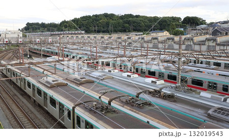 電車車両が数多く停車する東急電鉄の長津田検車区と、その遠景を走る東急田園都市線の電車 電車車両が数多く停車する東急電鉄の長津田検車区と、その遠景を走る東急田園都市線の電車 132019543