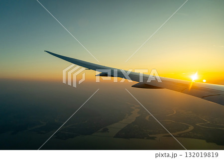 Airplane wing above Osaka coast during sunset descent flight 132019819