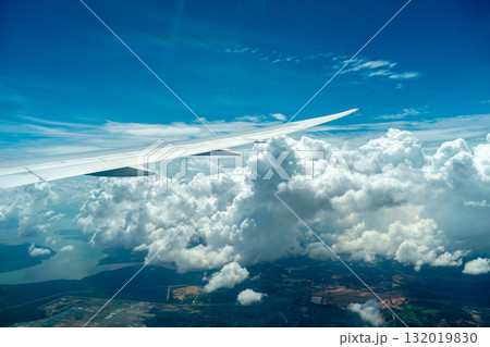 Airplane wing above coastline and clouds in bright sky 132019830