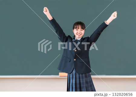 黒板の前に立ちガッツポーズをするブレザー姿の小学生,中学生,高校生の女子生徒 132020656