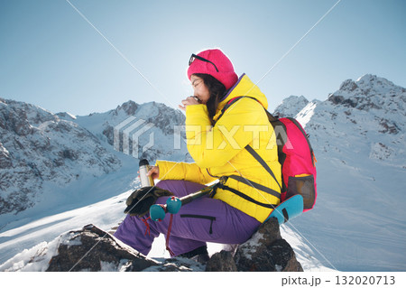 Woman in Vibrant Winter Gear Enjoying Hot Tea on Sunlit Mountain Summit During Clear Day 132020713