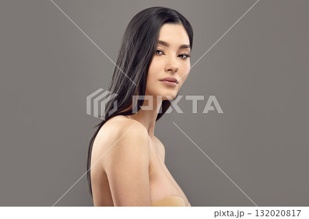 Asian female model with long dark hair looks to camera. 132020817