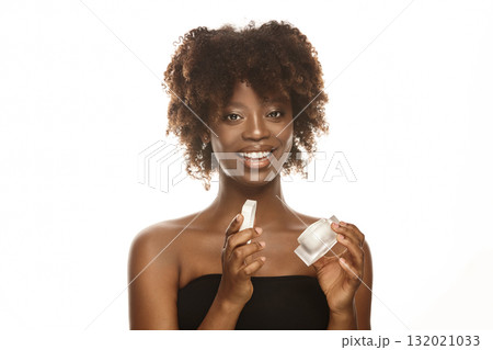 African american young woman shows cosmetic jar. 132021033