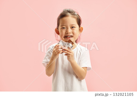 Happy Kid Girl Eating Greedily Big Chocolate Bar Isolated on Pink Background 132021105