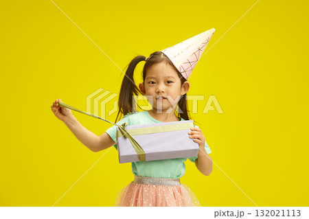 Lovely Chinese Child Girl Opening Birthday Box Gift Standing on Yellow Backdrop Lovely Chinese Child Girl Opening Birthday Box Gift Standing on Yellow Backdrop 132021113