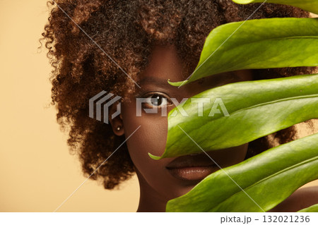 Female nude model of african ethnicity with monstera leaf. 132021236