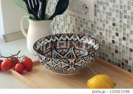 Retro-style ceramic bowl with geometric, floral patterns. Food in kitchen. Interior design and style. Mosaic tiles and kitchen countertops. 132021596