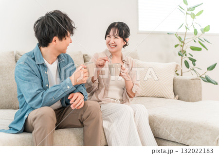 ソファでホットドリンクを飲みながらくつろぐ若いカップル,夫婦 ソファでホットドリンクを飲みながらくつろぐ若いカップル,夫婦 132022183
