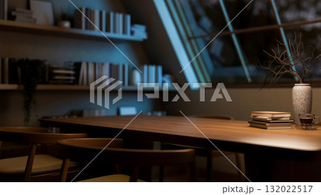 A coffee cup on wooden table and armchairs next to a bookshelf in the dim room with roof window. 132022517