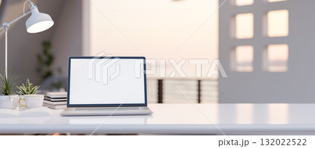White screen laptop with decors on a shiny white table with the blurred background of a wide terrace 132022522
