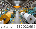 Inside a vast factory, large rolls of paper are staged for processing, highlighting the scale of industrial manufacturing and the path of material production 132022693